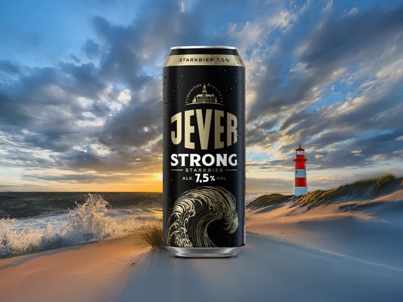 Eine Jever Strong Dose steht im Vordergrund vor einem Strand mit Leuchtturm, bei Sonnenuntergang.