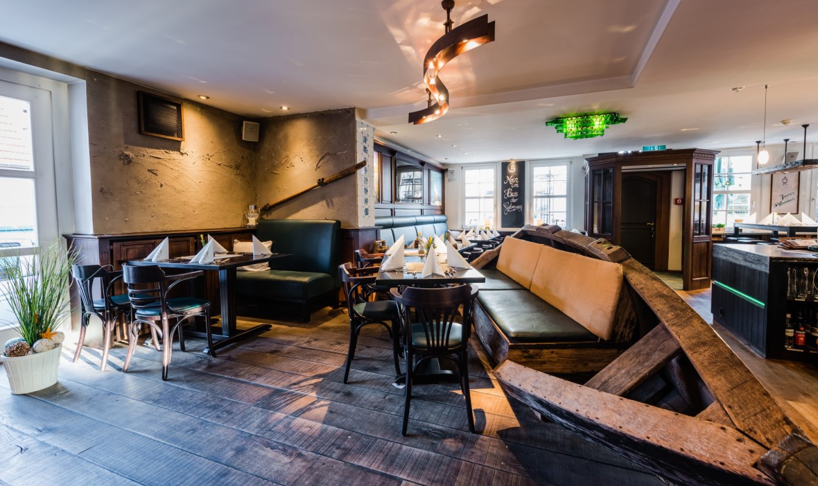 Das Bild zeigt das Innere eines Restaurants mit Holzmöbeln und einer gemütlichen Beleuchtung.