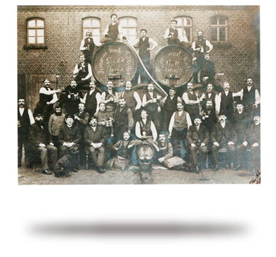 Eine Gruppe lachender Männer in historischer Kleidung posiert vor einem Gebäude.