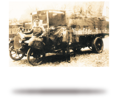 Zwei Personen stehen neben einem alten Lieferwagen auf einer Straße.