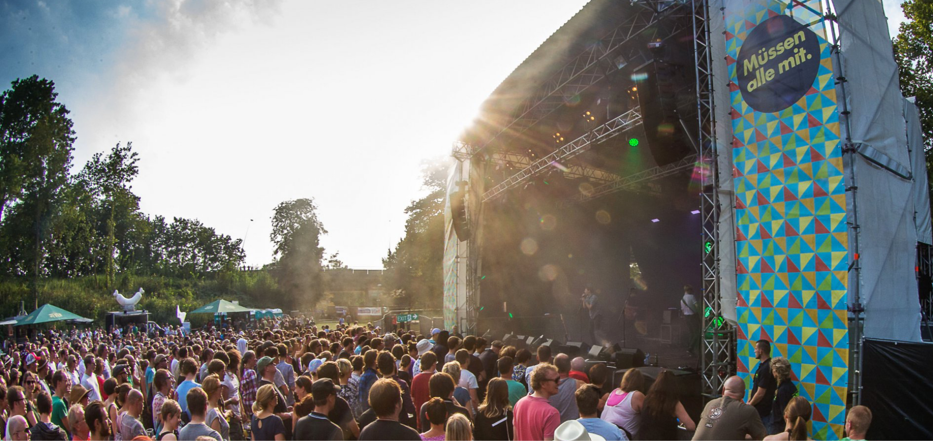 Eine Menschenmenge steht vor einer beleuchteten Bühne auf einem Outdoor-Musikfestival.