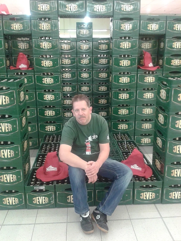 Ein Mann sitzt vor einem Stapel grüner Getränkekisten in einem Laden.