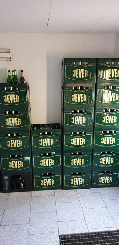 Mehrere grüne Getränkekisten gestapelt in einer Ecke, einige Flaschen sind sichtbar.