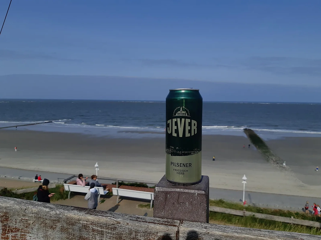 An einem Tannenbaum mit einer Lichterkette hängt ein Glas mit Bier, eine Jever-Bierflasche und eine Rakete.