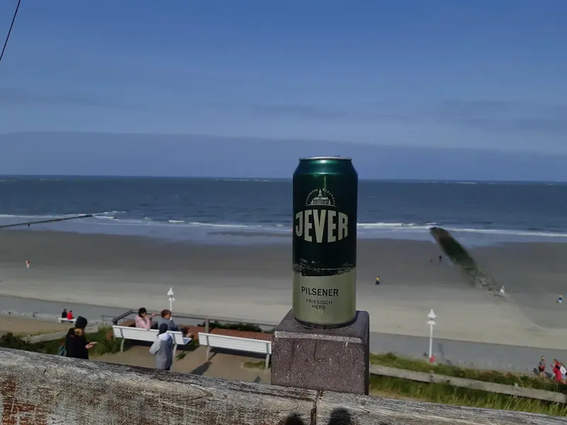 An einem Tannenbaum mit einer Lichterkette hängt ein Glas mit Bier, eine Jever-Bierflasche und eine Rakete.