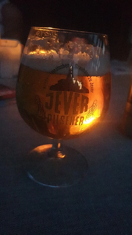 Bierglas mit Jever Pilsener und Schaumkrone, von innen durch Kerzenlicht beleuchtet. 