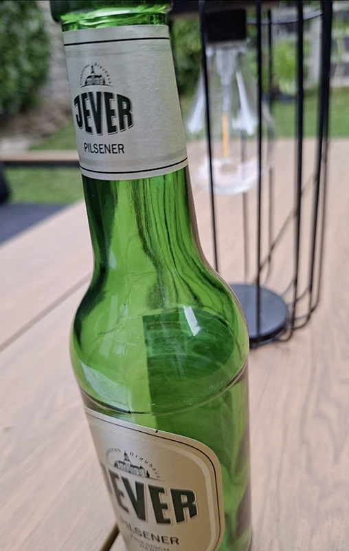 Eine grüne Jever Pilsener Flasche steht auf einem Holztisch.