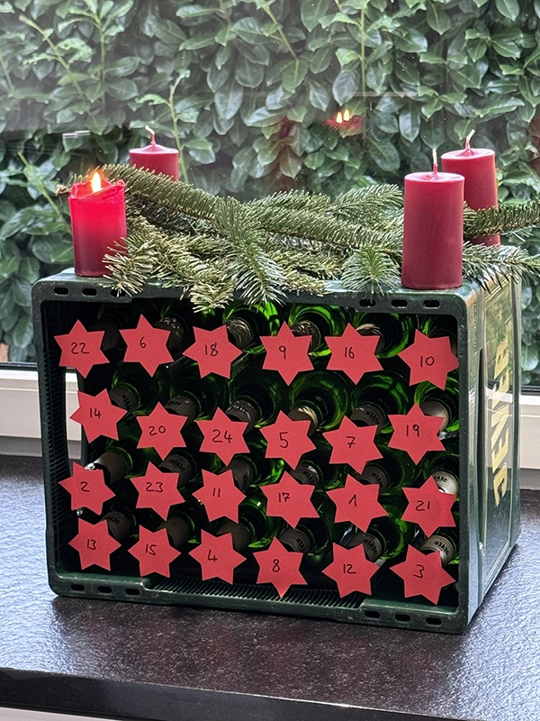 Ein umgekippter Jever-Bierkasten, auf dessen Flaschen Nummern von eins bis 24 kleben. Der Bierkasten fungiert als Adventskalender.