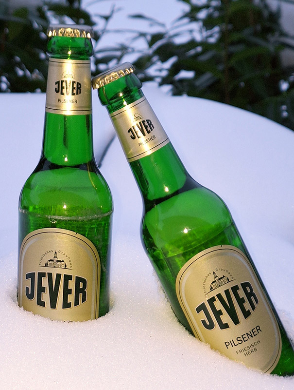 Zwei Jever-Bierflaschen stecken nebeneinander im Schnee.