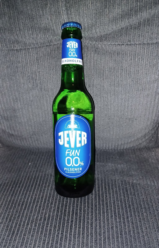 Eine Jever-Bierflasche lehnt an der Rückenlehne einer Stoffcouch.