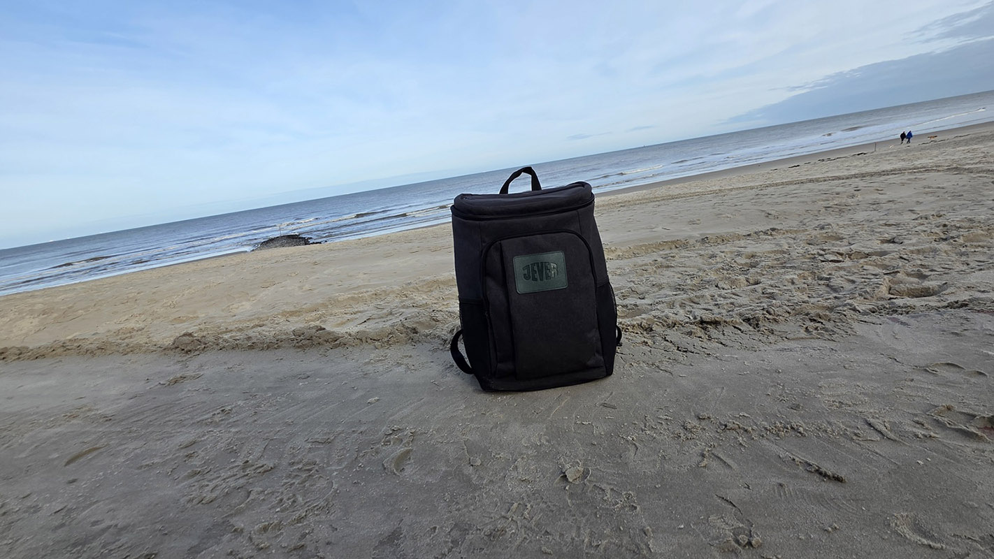 Ein Jever-Rucksack steht auf dem Sand eines Strandes.