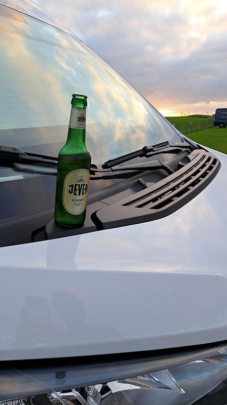 Eine Jever-Bierflasche steht auf der Motorhaube eines Autos.