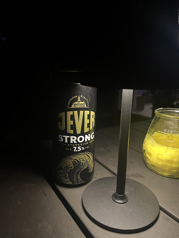 Eine Jever-Bierdose wird in einem dunklen Raum von einer Tischlampe beleuchtet.