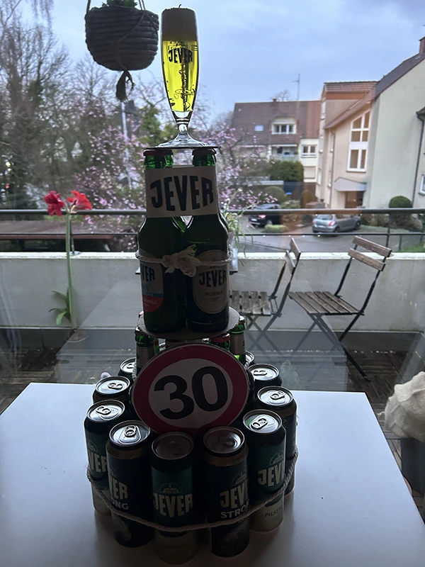Flaschen- und Dosenpyramide mit Jever-Bier, darüber ein Glas, dekoriert mit einer 