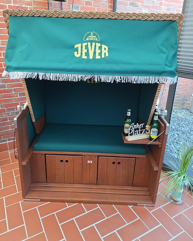 Strandkorb mit Jever-Logo, auf dem Sitzpolster stehen zwei Bierflaschen auf einem Tablett mit 