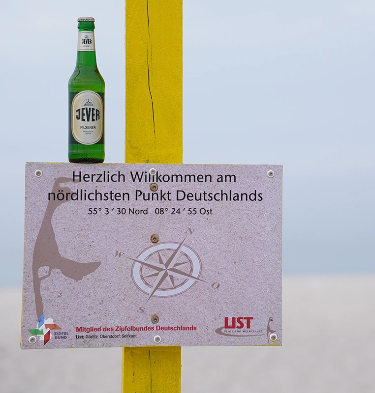 Flasche Jever Pilsener steht auf einem Schild mit der Aufschrift Herzlich Willkommen am Nördlichster Punkt Deutschlands.