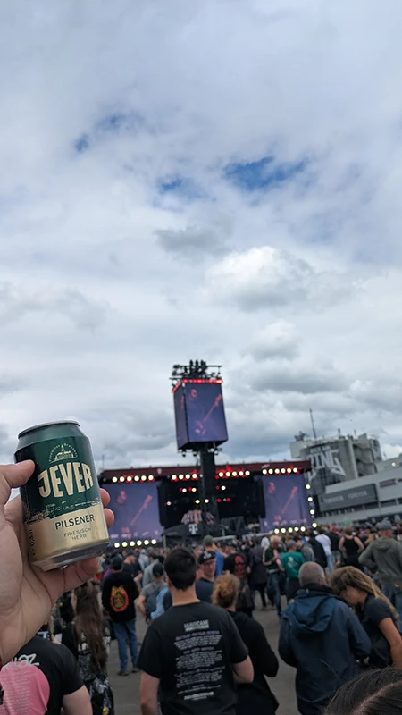 Person hält eine Jever-Bierdose hoch, während sie ein Konzert auf einer großen Bühne mit vielen Zuschauern besucht.