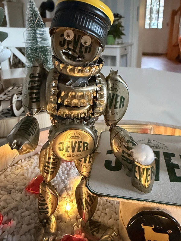 Einzigartiger Roboter aus Jever-Bierdosen und Kronkorken, platziert auf einem Tisch mit festlicher Beleuchtung.