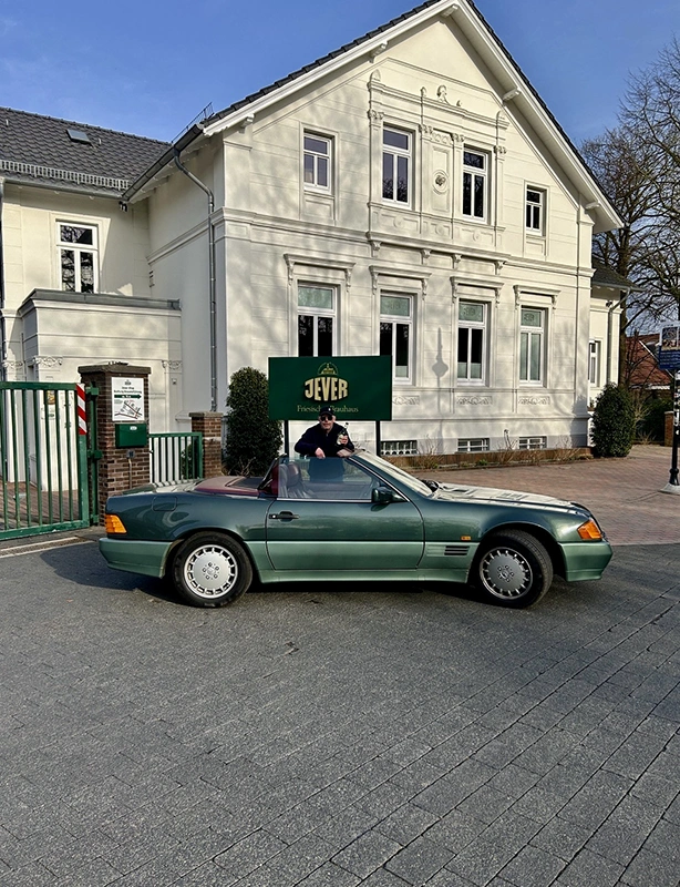 Grünes Cabriolet steht vor dem Friesischen Brauhaus zu Jever. Eine Person steht am Fahrzeug.