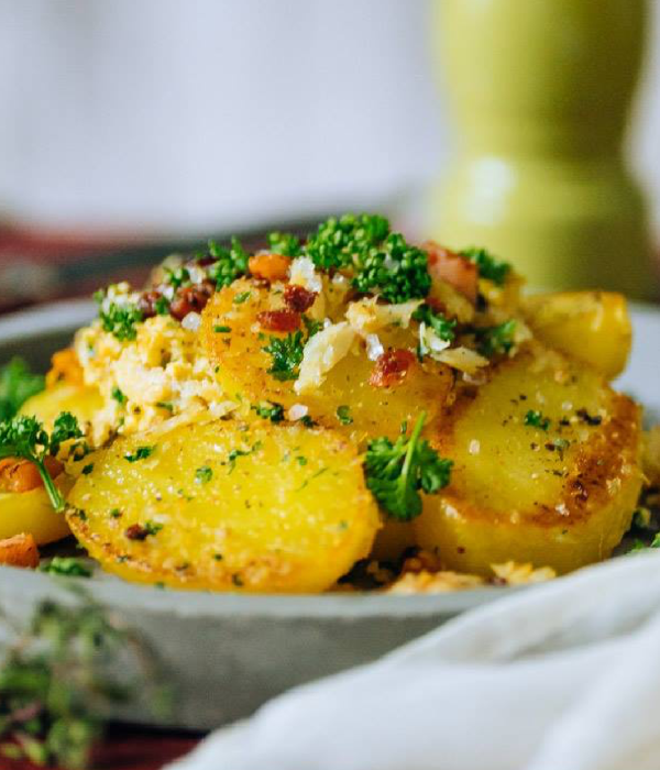 Gebratene Kartoffelscheiben sind mit Petersilie und Krümeln garniert.