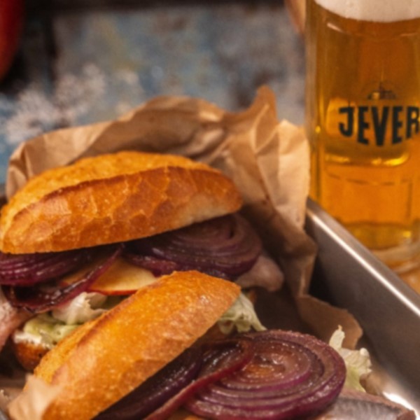 Ein Sandwich mit Rindfleisch, roten Zwiebeln und Salat wurde neben einem Bierglas serviert.